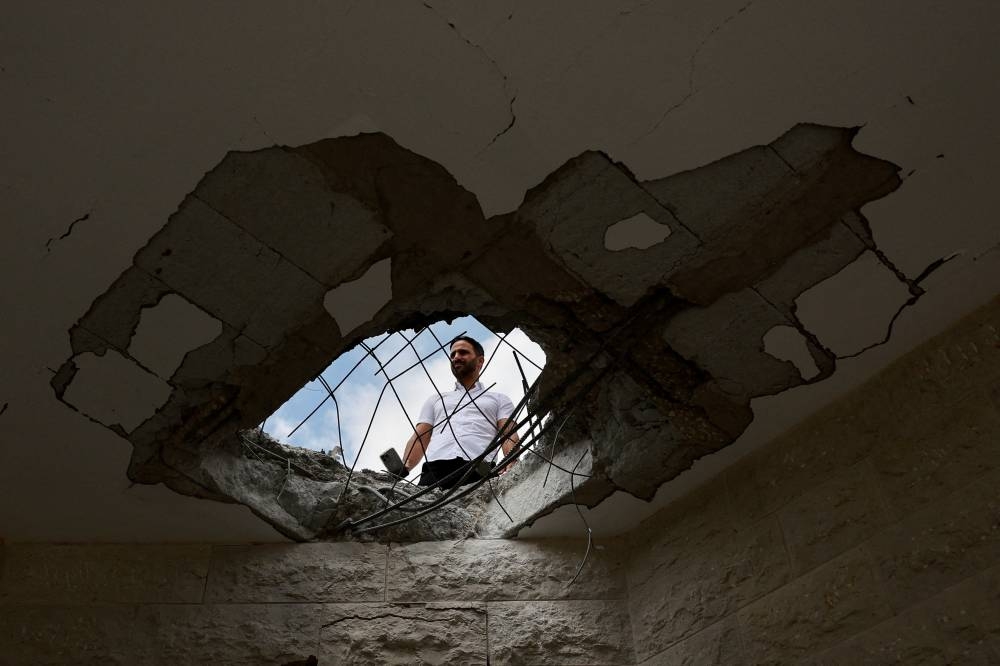 An official property surveyor assesses the damage to a residential building following a direct-hit from a projectile, after Hezbollah launched hundreds of rockets and drones towards Israe, in northern Israel on Sunday. REUTERS