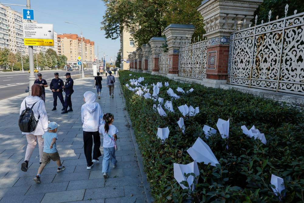 People walk past paper planes referring to the logo of the Telegram messaging app, which were placed during a gathering in support of freedom of expression held by representatives of Russia's New People political party, following the arrest of Telegram founder and CEO Pavel Durov, near the French embassy in Moscow, Russia Sunday. REUTERS
