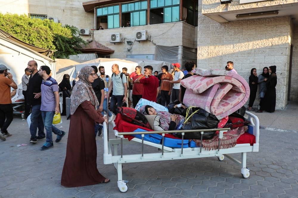 Palestinian patients fearing an Israeli ground operation are assisted to flee Al-Aqsa Martyrs hospital, after Israeli army ordered the evacuation of nearby areas, in Deir Al-Balah in the central Gaza Strip Sunday.