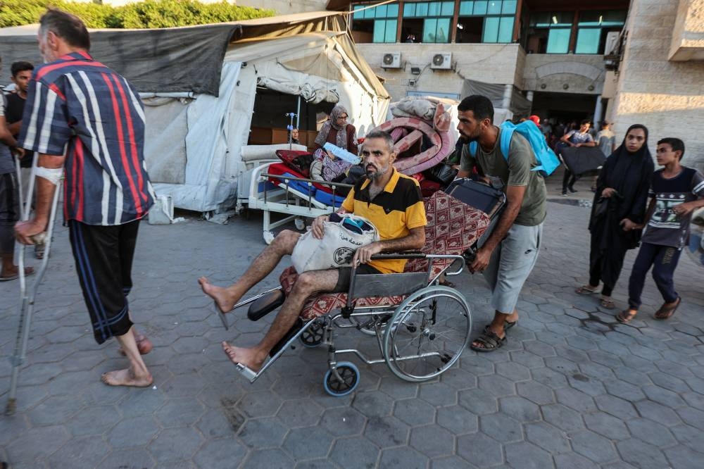Palestinian patients fearing an Israeli ground operation are assisted to flee Al-Aqsa Martyrs hospital, after Israeli army ordered the evacuation of nearby areas, in Deir Al-Balah in the central Gaza Strip Sunday.
