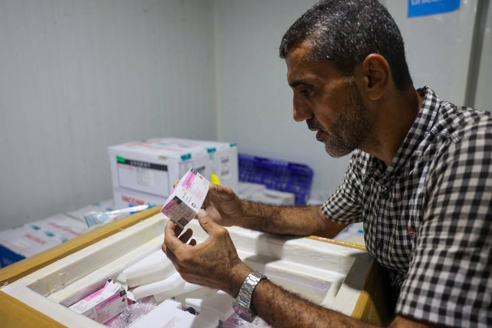A worker inspects a box containing polio vaccines provided with support from UNICEF to the Gaza Strip through the Karm Abu Salem crossing, at a depot belonging to Gaza's health ministry, Sunday.
