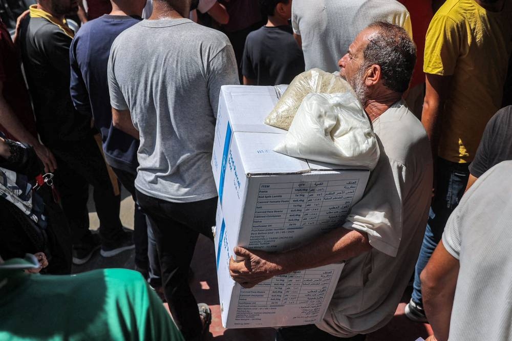 People receive humanitarian aid packages provided by the United Nations Relief and Works Agency for Palestine Refugees (Unrwa) from a warehouse in central Gaza Tuesday.