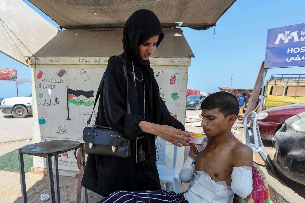 Diaa Al-Adini is helped by his sister Aya to drink iced juice on a beach outside a field hospital, in Deir Al-Balah in the central Gaza Strip,on Tuesday. REUTERS
