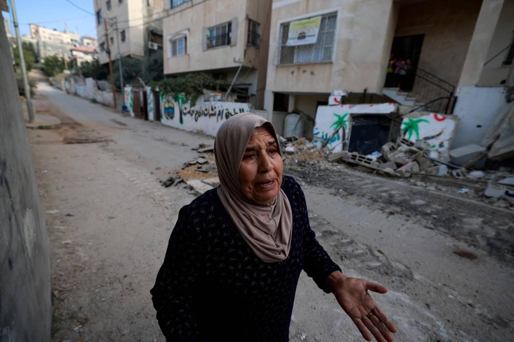A Palestinian woman reacts as she walks along a street damaged during a raid in the Nur Shams camp near the city of Tulkarem in the Israeli-occupied West Bank, on Wednesday. AFP