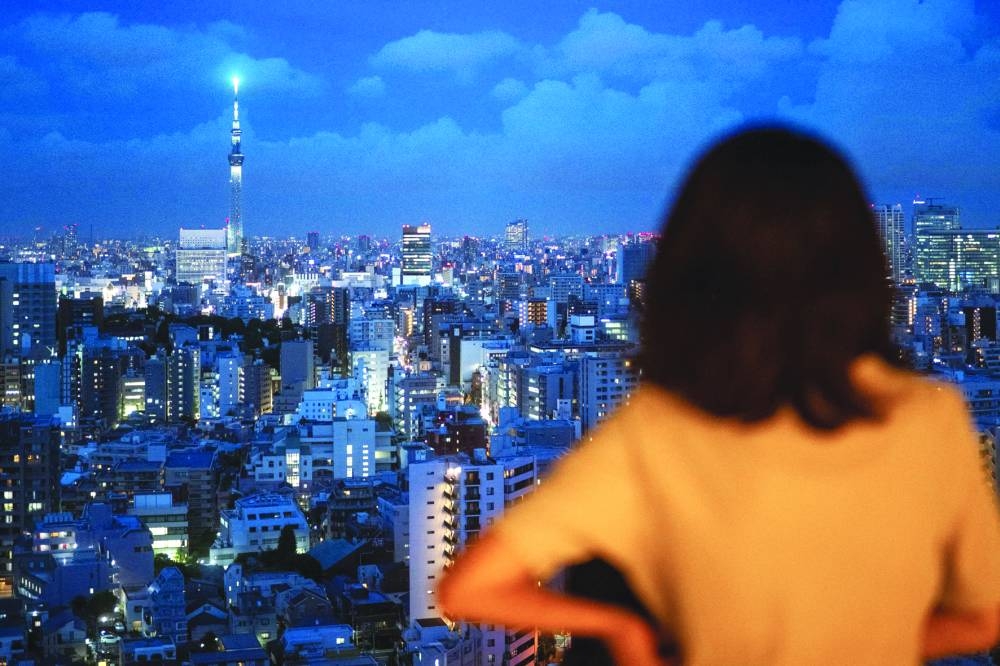 
A woman looks at the city skyline with clouds in the distance at dusk from the Bunkyo Civic Center Observation Deck in Tokyo. 