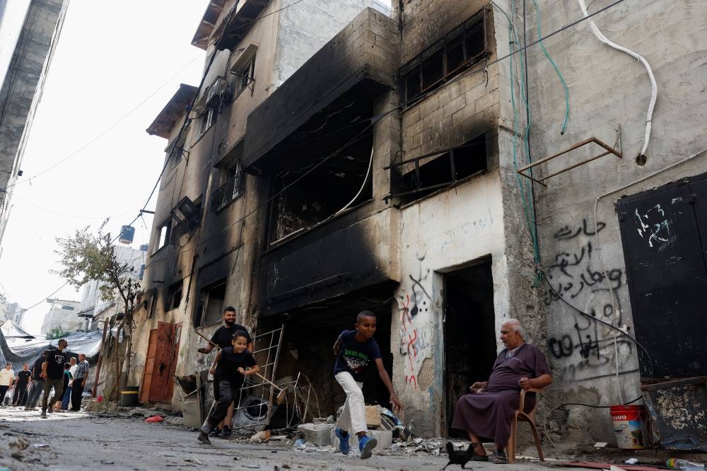 Children pass by a damaged house, following an Israeli military raid, in Tulkarm, in the Israeli-occupied West Bank, on Friday. REUTERS