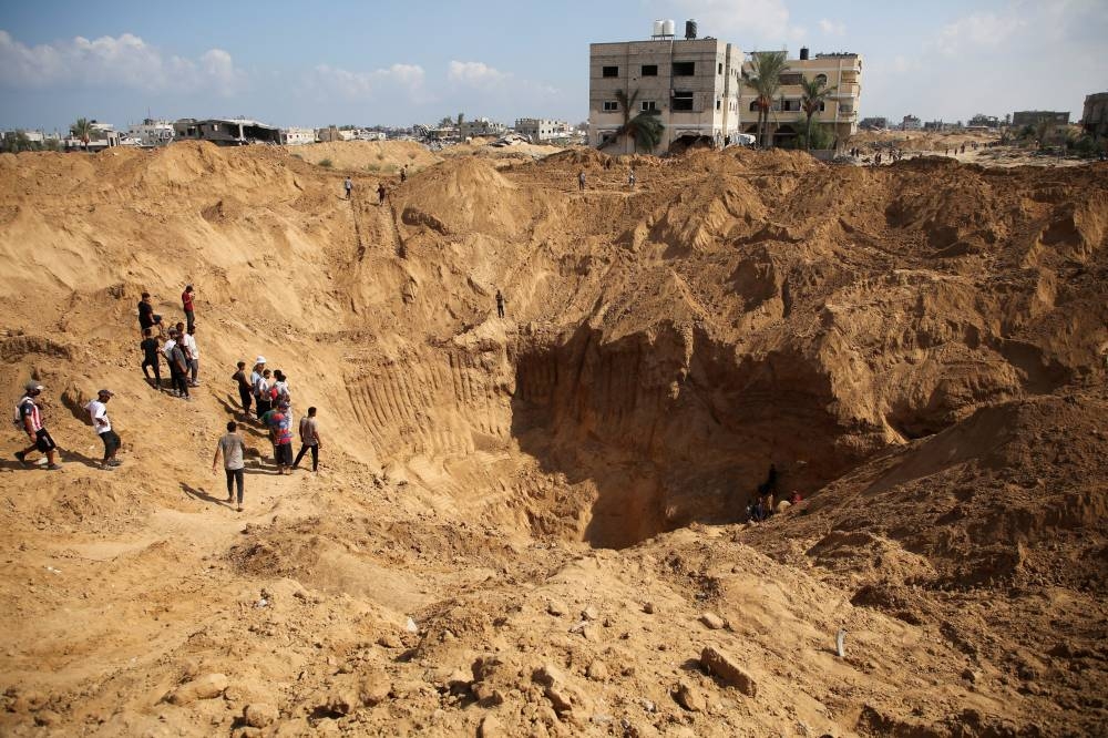 Palestinians gather to inspect a site excavated by Israeli forces after their withdrawal from the area, following a ground operation in Khan Younis, in the southern Gaza Strip, Friday, REUTERS