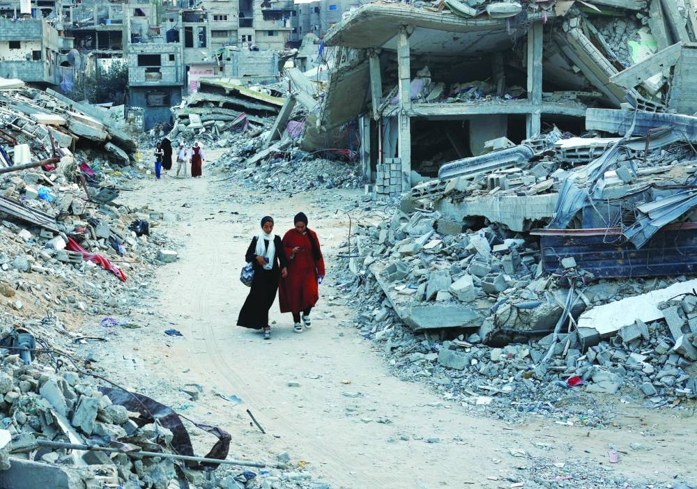 Palestinians walk amidst the rubble of buildings destroyed after an Israeli strike, in Khan Younis, in the southern Gaza Strip Sunday.