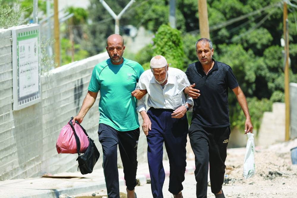 
Palestinians walk, as they evacuate their home during an Israeli raid in Jenin camp, in the West Bank. 
