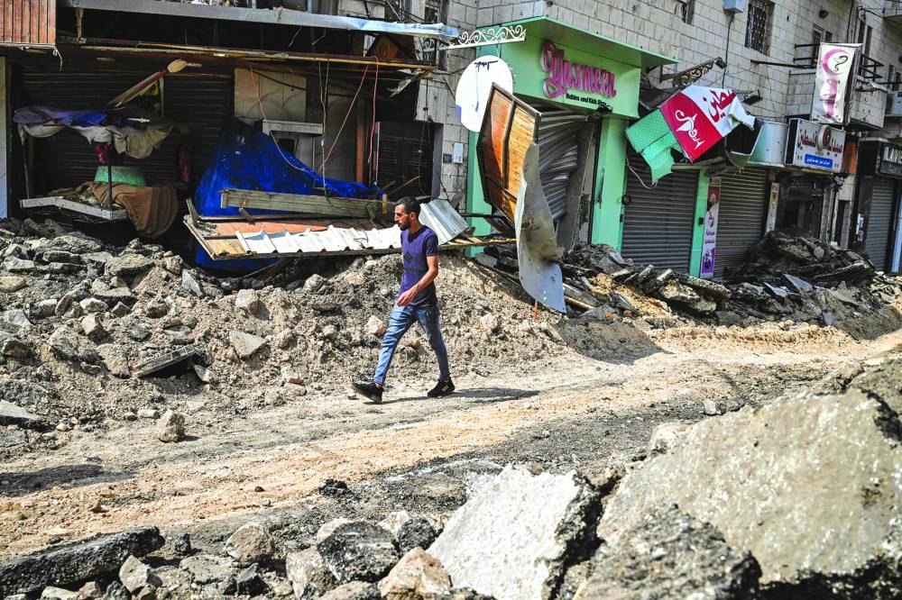 
A Palestinian man walks past damaged shops on a street torn up by bulldozers during an Israeli raid in the occupied West Bank city of Jenin, yesterday. 