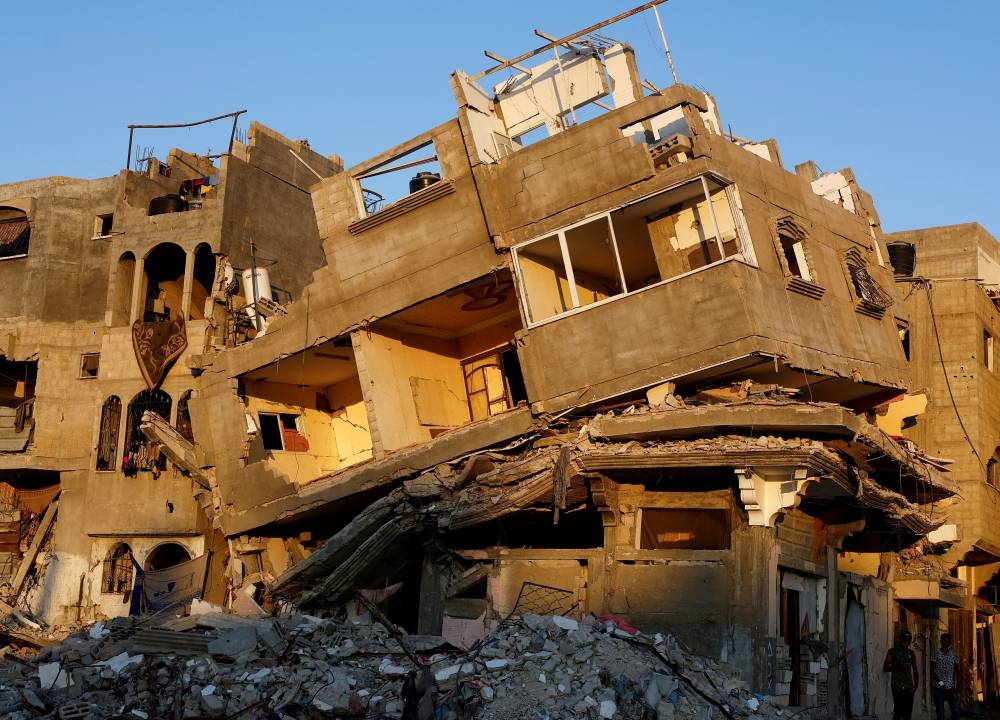 Palestinians stand near buildings destroyed after an Israeli strik in Khan Younis, in the southern Gaza Strip on Sunday.  REUTERS