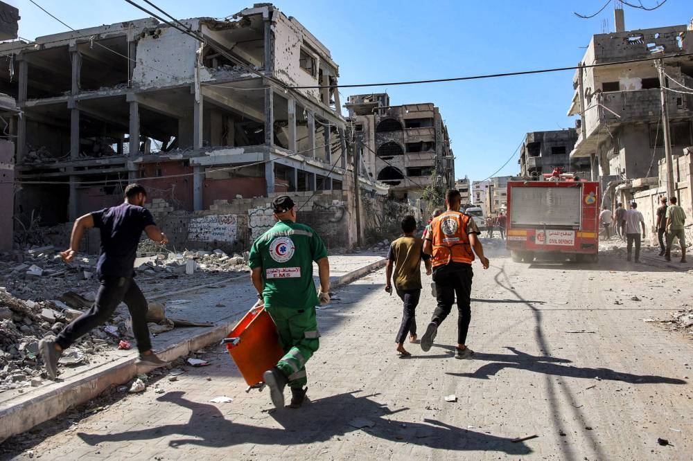 Palestinian civil defence members walk towards a fire engine by destroyed buildings in the Sheikh Radwan neighbourhood in the north of Gaza City on Tuesday. AFP
