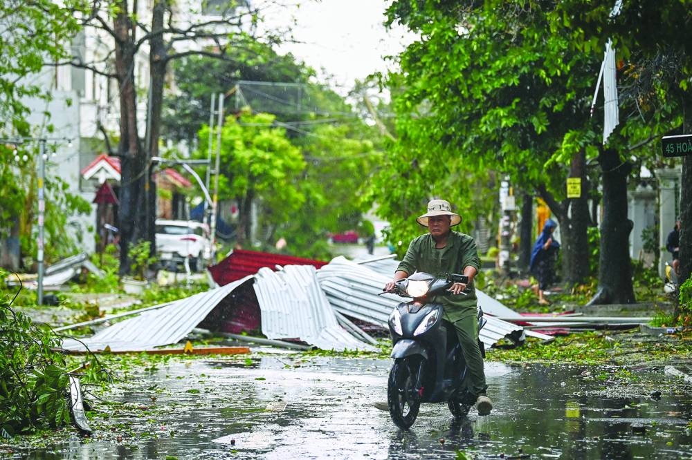 
A man rides a scooter past debris on a street after Super Typhoon Yagi hit Hai Phong yesterday. 