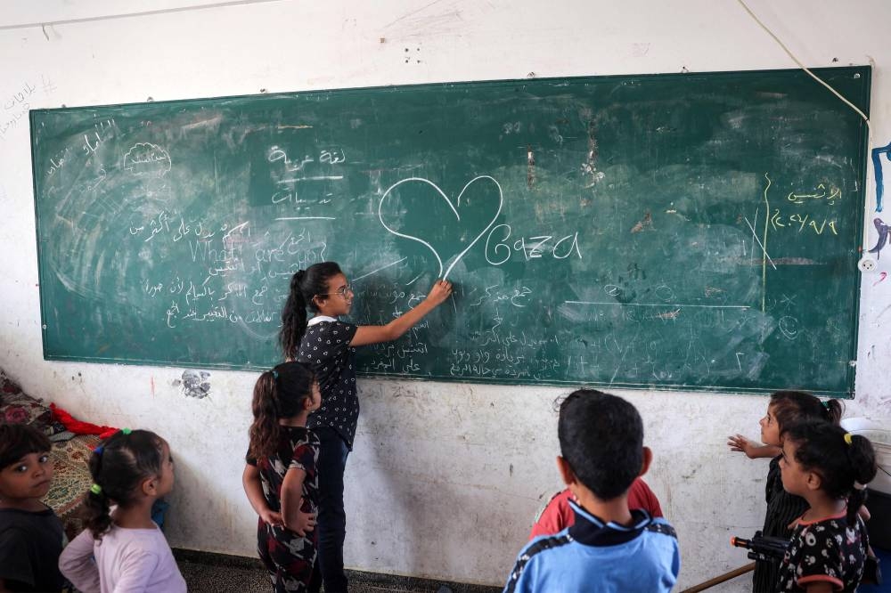 A girl draws on a blackboard in a classroom sheltering people displaced by conflict at a school run by the UNRWA in Deir el-Balah in the central Gaza Strip on Monday. AFP