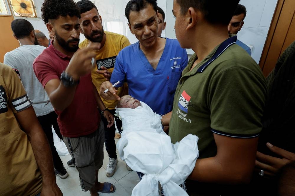  A mourner holds the body of Palestinian infant Jad Al-Bayouk, who was killed in an Israeli strike along with other family members, at Nasser hospital in Khan Younis, in the southern Gaza Strip, on Tuesday. REUTERS
