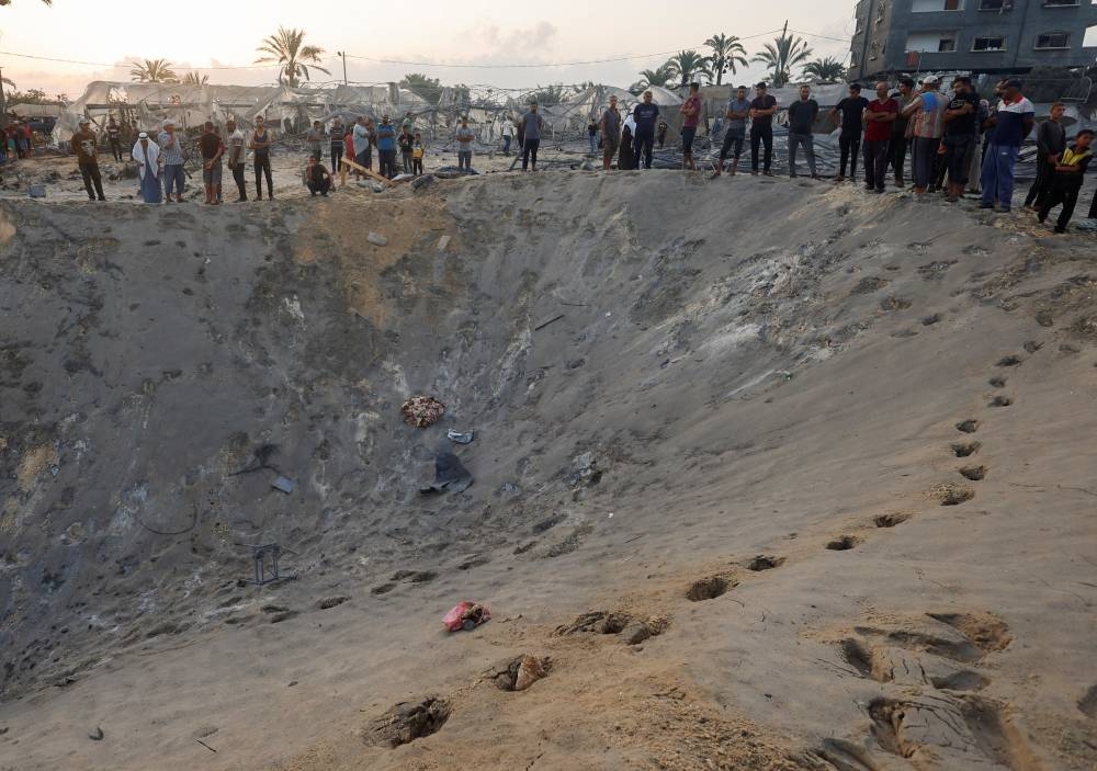 Palestinians inspect the site following Israeli strikes on a tent camp sheltering displaced people at the Al-Mawasi area in Khan Younis, in the southern Gaza Strip, on Tuesday. REUTERS
