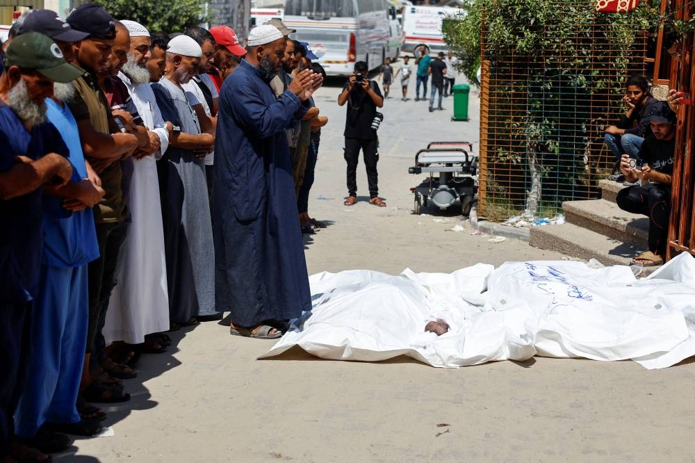  People pray next to the bodies of Palestinians from Al-Bayouk family, including infant Jad, who were killed in an Israeli strike, at Nasser hospital in Khan Younis, in the southern Gaza Strip, on Tuesday. REUTERS