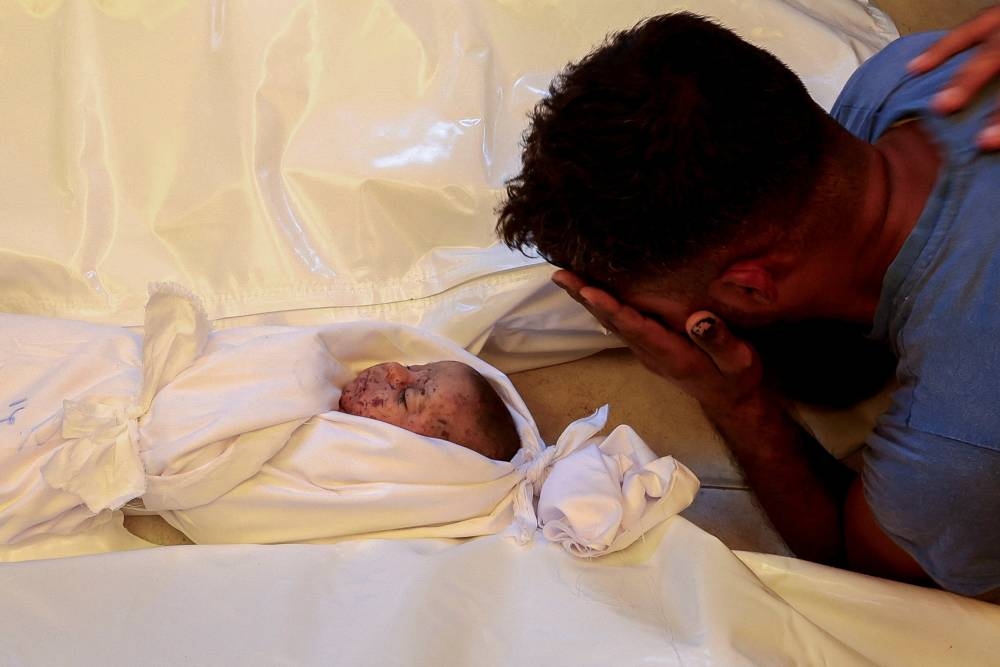  The father of Palestinian infant Jad Al-Bayouk, who was killed in an Israeli strike along with other family members, reacts next to his body, at Nasser hospital in Khan Younis, in the southern Gaza Strip, on Tuesday. REUTERS