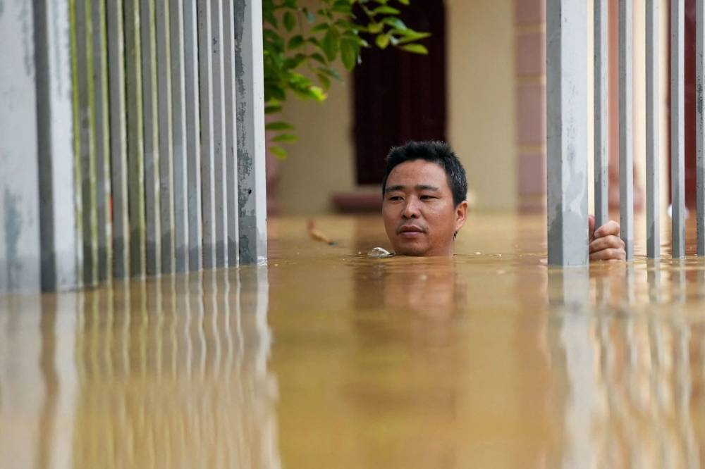 A man wades through flood waters outside his house in Thai Nguyen province on Tuesday. AFP