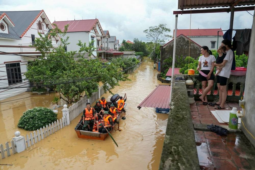Women look at rescue workers on a boat in front of their house in Thai Nguyen province on Tuesday. AFP