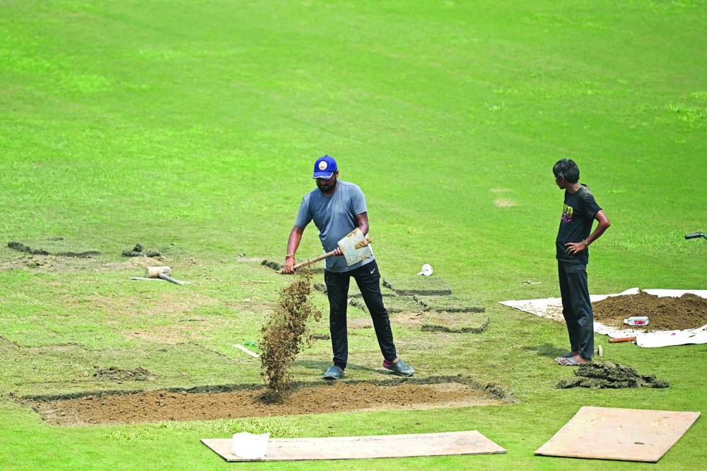 Groundsmen repair the outfield with artificial grass before the start of the one-off Test between Afghanistan and New Zealand at the Shaheed Vijay Singh Pathik Sports Complex in Greater Noida on Tuesday. (AFP)