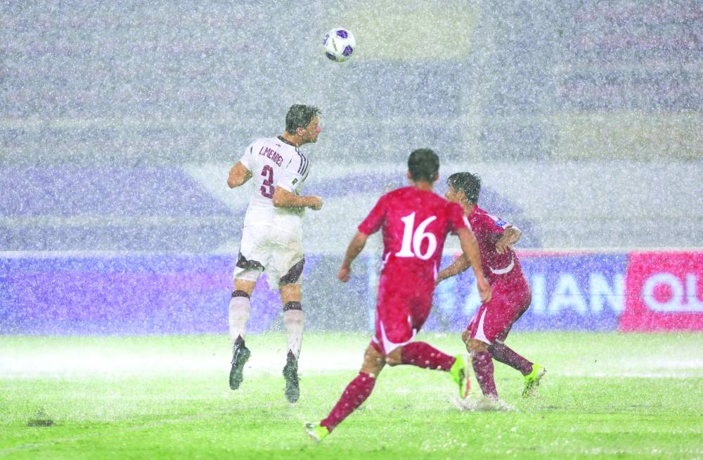 
Qatar’s Lucas Mendes heads the ball in the pouring rain. 