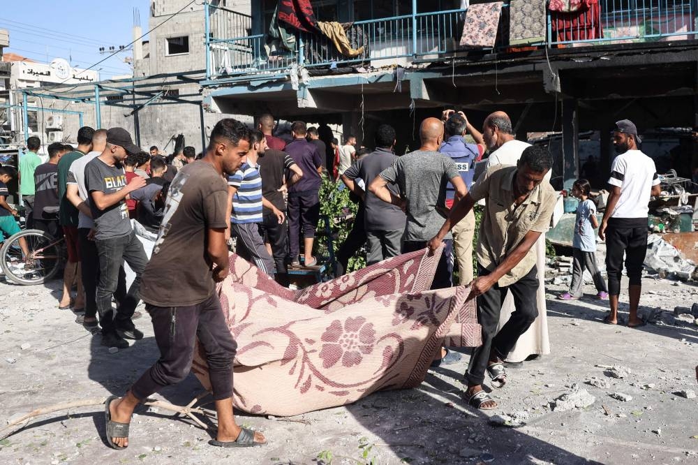 People use a blanket to transport a victim after an Israeli air strike hit a school in Nuseirat, in the central Gaza Strip on Wednesday. AFP