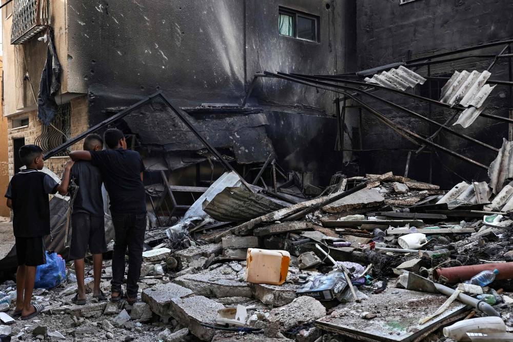 Palestinian children stand amid the rubble in front of a burnt building, after an Israeli army raid in Tulkarem in the north of the occupied-West Bank, on Thursday. AFP