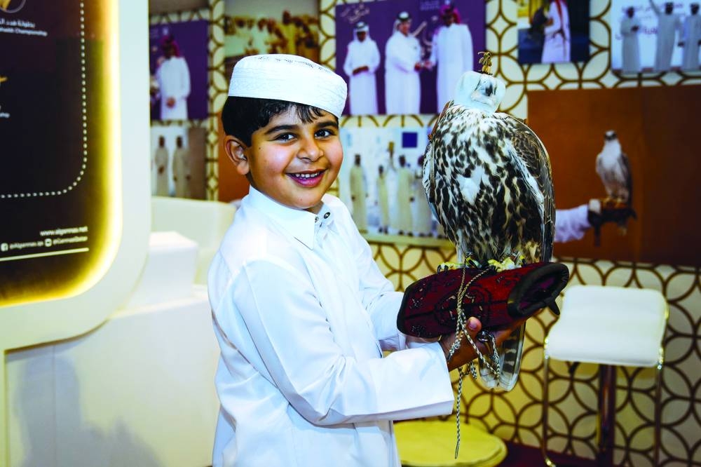 A young falconer is all smiles as he poses with a falcon at the event.