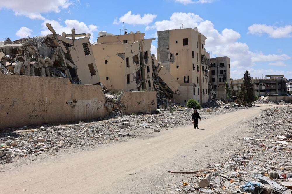 A Palestinian woman walks in front of buildings heavily damaged in Israeli bombing, in Beit Lahia in the northern Gaza Strip on Saturday. AFP