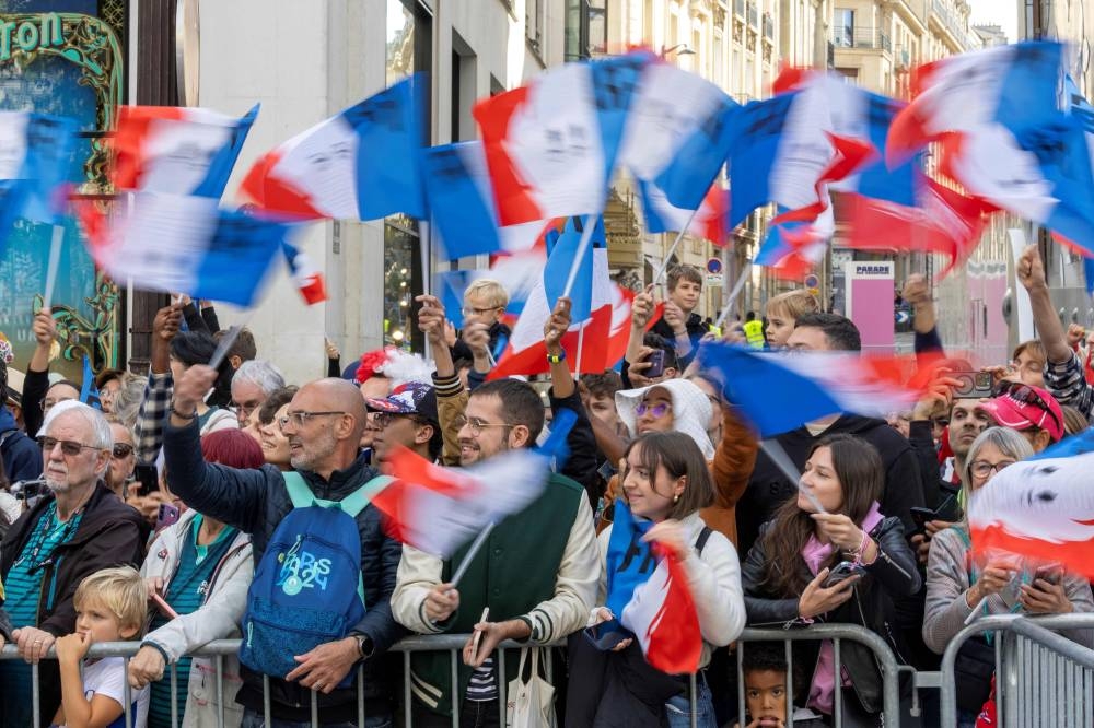 Sports fans wave French flags during a parade of French athletes who competed in the Paris 2024 Olympic and Paralympic Games on the Champs-Elysees avenue in Paris on, Saturday. AFP