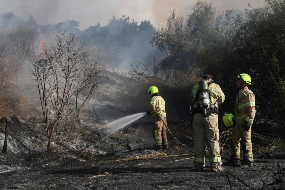 Responders put out a fire in the area of Lod, near Tel Aviv, in central Israel on Sunday. AFP