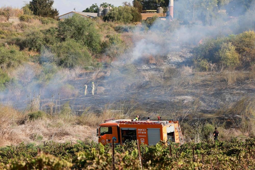 Responders put out a fire in the area of Lod, near Tel Aviv, in central Israel on Sunday. AFP