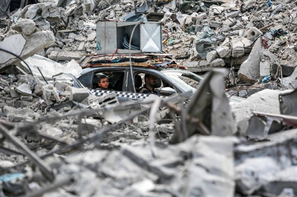 A vehicle moves past the rubble of collapsed buildings in Khan Yunis in the southern Gaza Strip on Monday. AFP