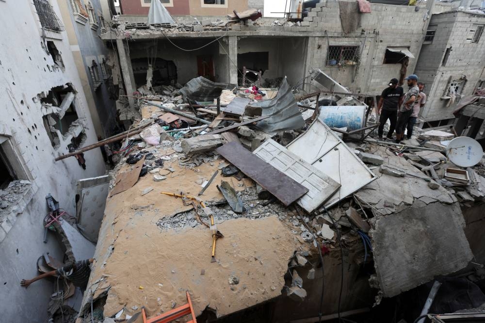 Palestinians inspect the site of an Israeli strike on a house in Nuseirat in the central Gaza Strip, Monday. REUTERS