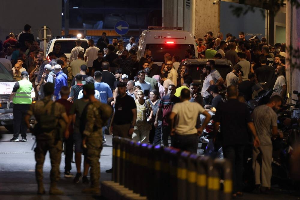 People gather at the entrance of the American University of Beirut Medical Center, on Tuesday, after explosions hit locations in several Hezbollah strongholds around Lebanon. AFP