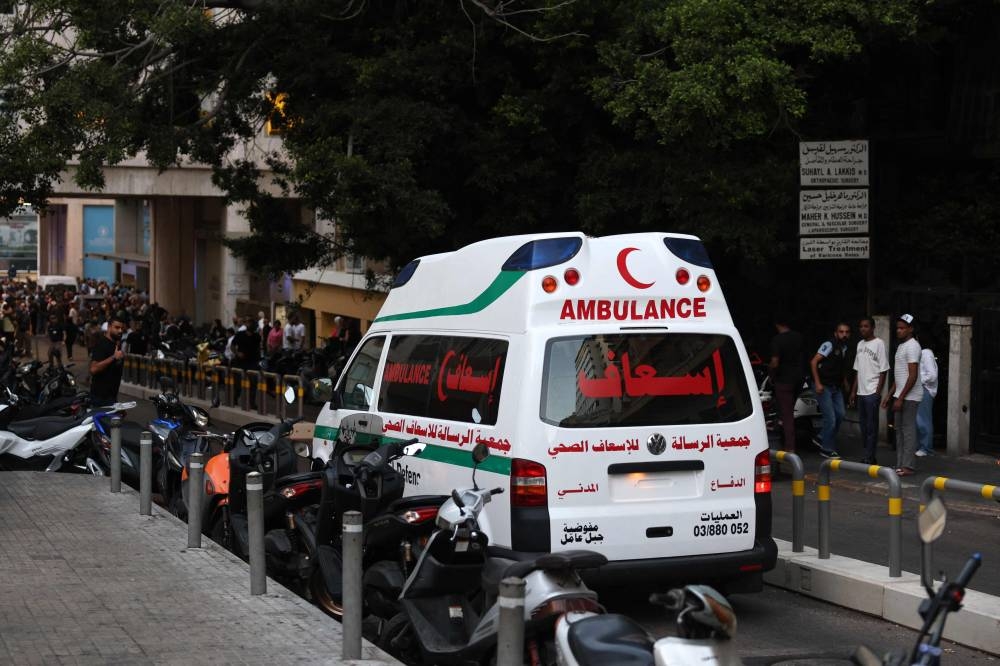 An ambulance rushes wounded people to the American University of Beirut Medical Center, on Tuesday, after explosions hit locations in several Hezbollah strongholds around Lebanon. AFP