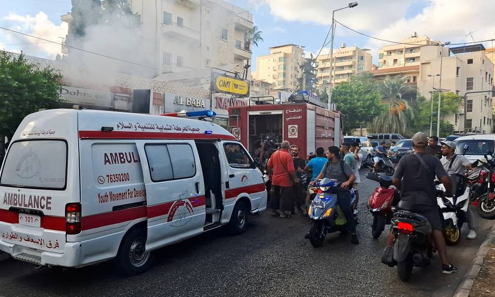 People gather as smoke rises from a mobile shop in Sidon, Lebanon on Wednesday. REUTERS