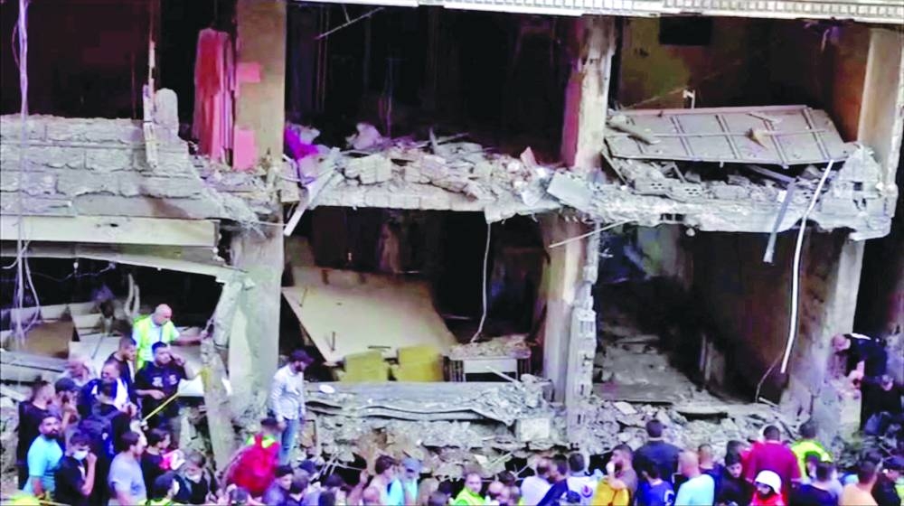 Rescuers gather next to a destroyed building, after an Israeli strike targeted a top Hezbollah military official, Lebanese authorities said in Beirut, yesterday.