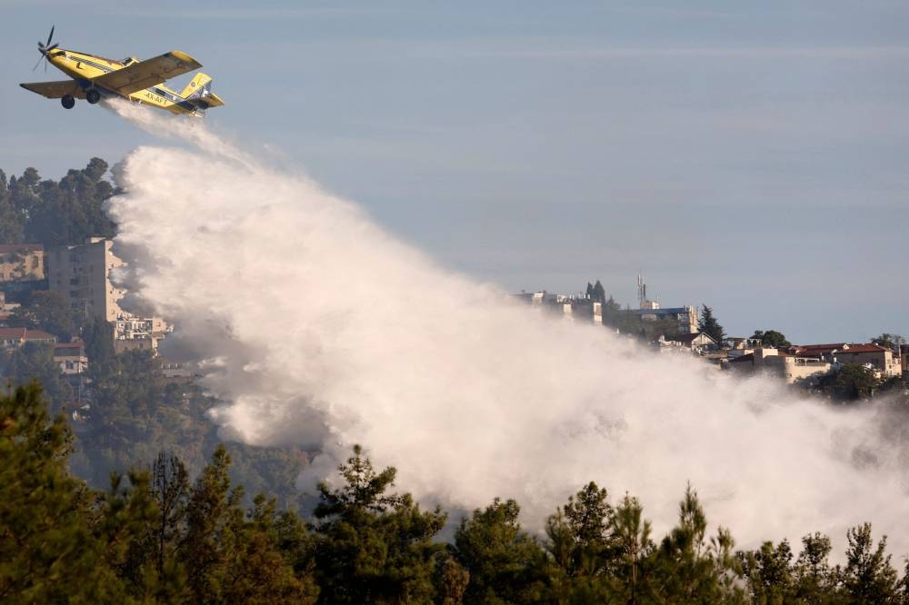 A firefighting aircraft releases flame retardant to extinguish fires caused by rockets launched from southern Lebanon which landed on the outskirts of Safed, in the upper Galilee on Saturday. AFP