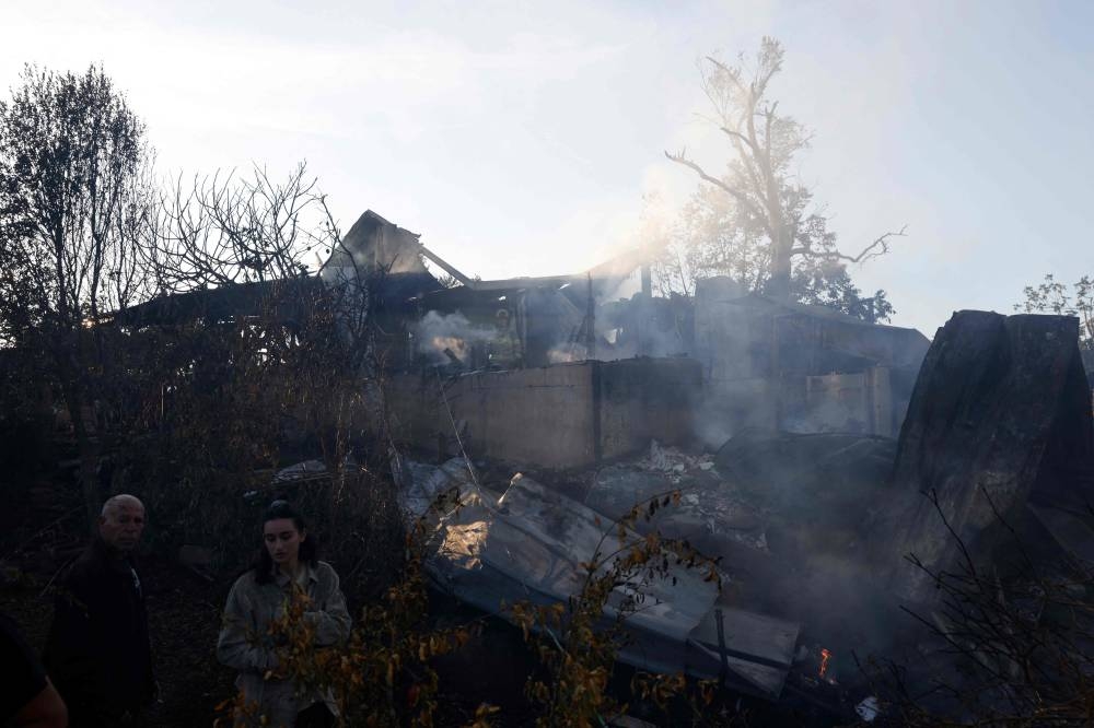Israelis walk next to a building hit by rockets fired from Lebanon, in Kadita on the outskirts of Safed near the border with Lebanon on Tuesday. AFP