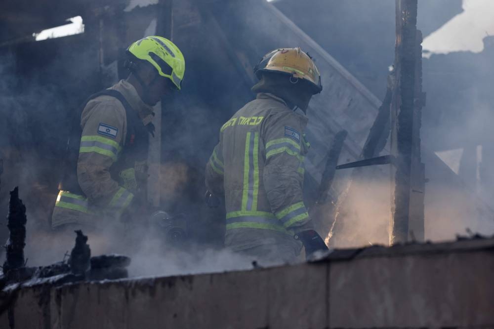 Firefighters inspect the damage at the site where rockets fired from Lebanon hit, in Kadita on the outskirts of Safed near the border with Lebanon on Tuesday. AFP