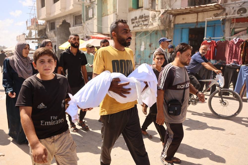 A Palestinian man carries a body during a funeral after an Israeli strike on a school housing displaced Palestinians in Gaza City's Zaytoun neighbourhood, on Saturday. AFP