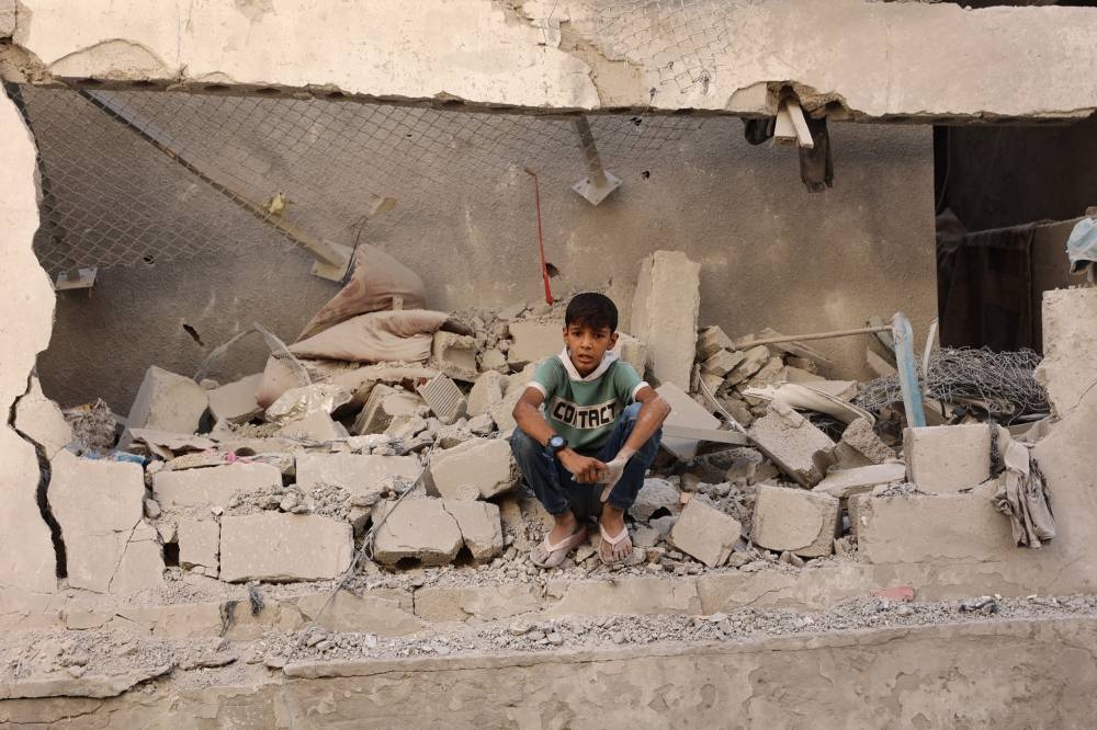 A Palestinian boy sits amongst the debris at the site of an Israeli strike on a school housing displaced Palestinians in Gaza City's Zaytoun neighbourhood, on Saturday. AFP