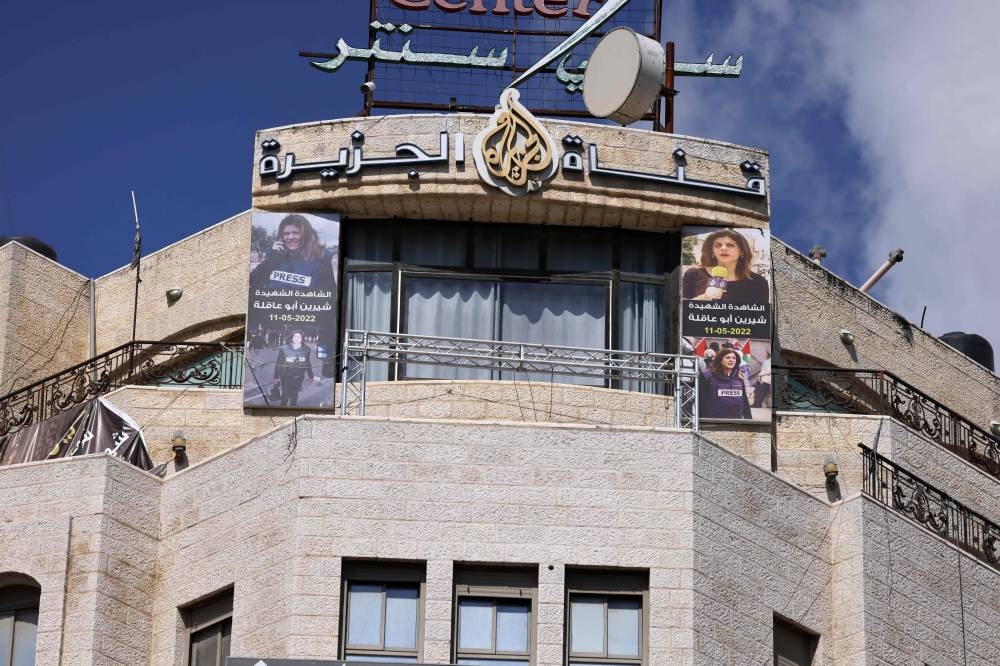 Pictures of slain al-Jazeera journalist Shireen Abu Akleh hang on the facade of the building housing the television station's office in Ramallah in the occupied West Bank, after Israel issued a 45-day closure order on Sunday. AFP