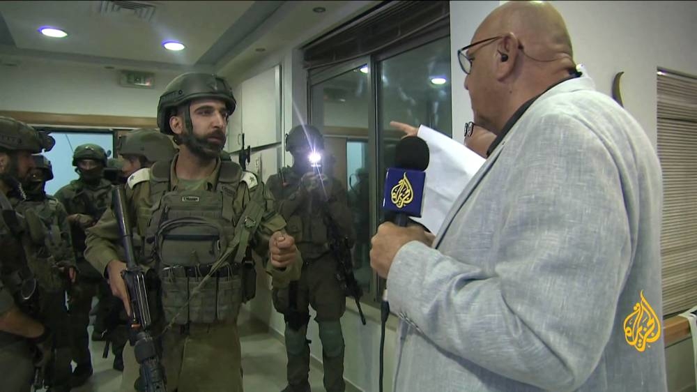 An image grab from footage distributed by the Doha-based Al-Jazeera TV on September 22, 2024 shows an Israeli soldier speaking with Walid Al-Omari, bureau chief of Al Jazeera in Jerusalem and Ramallah, upon entering Al Jazeera's office in Ramallah, in the West Bank to issue a 45-day closure order on September Saturday. AL JAZEERA / AFP