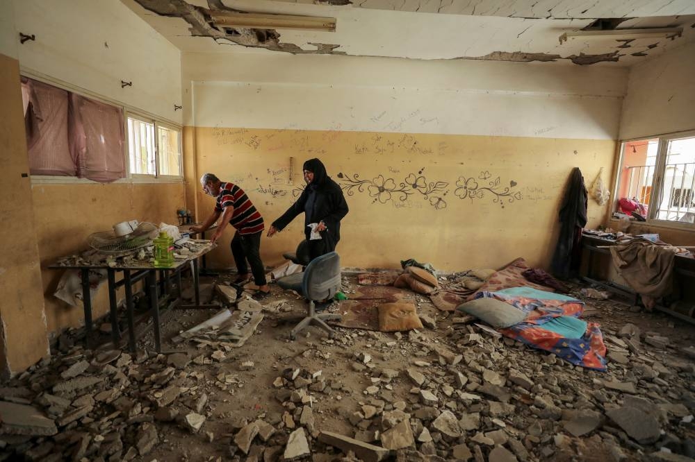 Palestinians inspect the damage to a school sheltering displaced people after it was hit by an Israeli strike at Beach refugee camp in Gaza City, Sunday. REUTERS