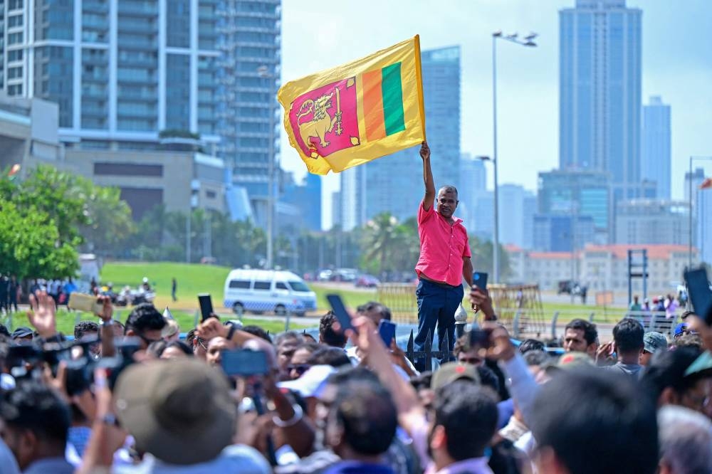 A supporter of Sri Lanka's newly elected President Anura Kumara Dissanayaka, waves country's national flag near the Presidential Secretariat after Dissanayaka's swearing-in ceremony in Colombo on Monday. AFP