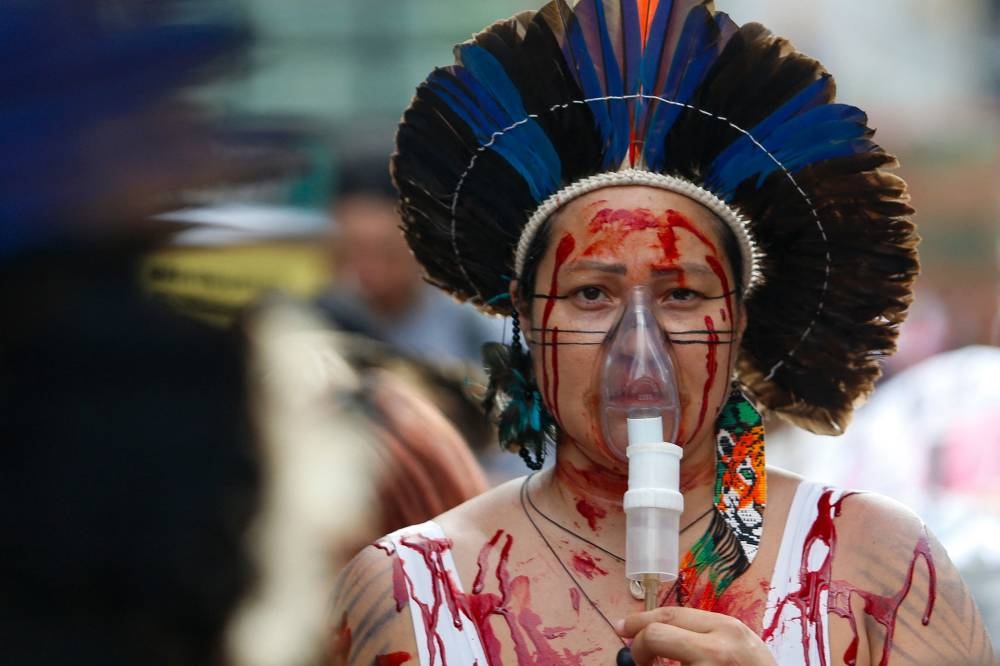 A Brazilian indigenous woman wears a portable oxygen mask during a march for climate justice and against wild fires affecting the entire country in Sao Paulo, Brazil, on Sunday. AFP