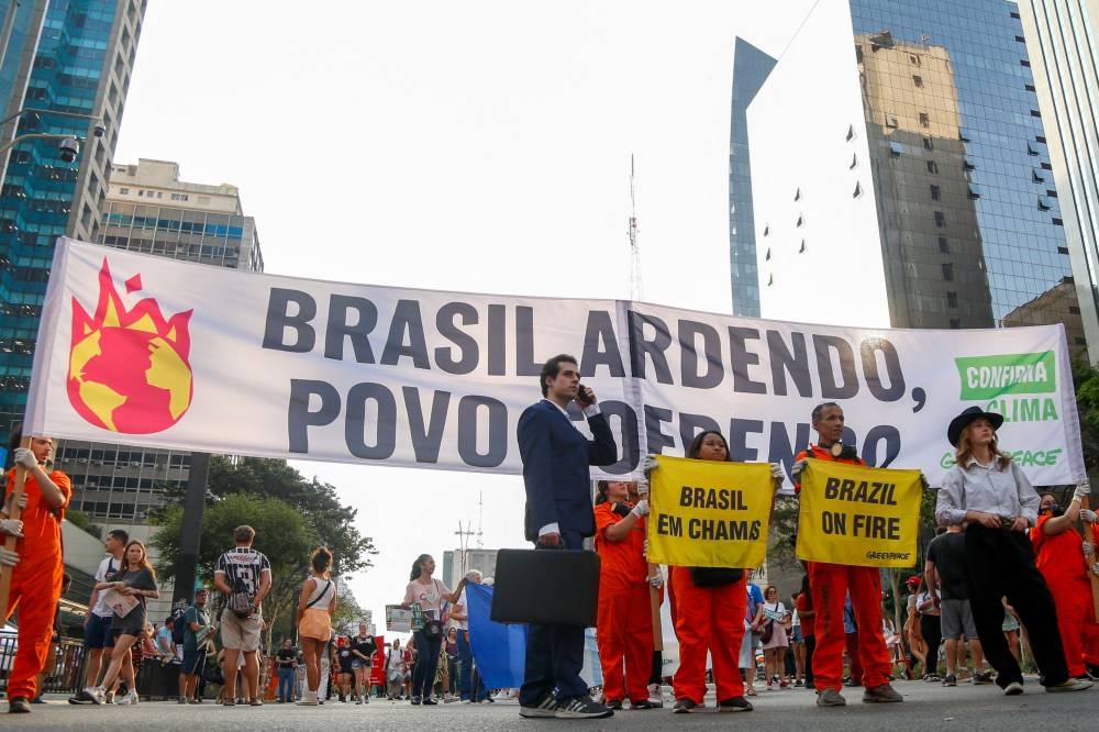 Greenpeace activists hold a banner reading "Brazil burning, people suffering" while taking part in a march for climate justice and against wild fires affecting the entire country in Sao Paulo, Brazil, on Sunday. AFP